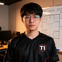 T1战队首席数据分析师肖像，一位戴眼镜的亚洲男性，穿着印有T1标志的黑色队服，背景是训练室内的战术白板